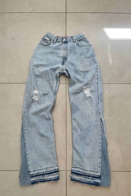 Pair of light blue jeans with distressing on a tiled floor