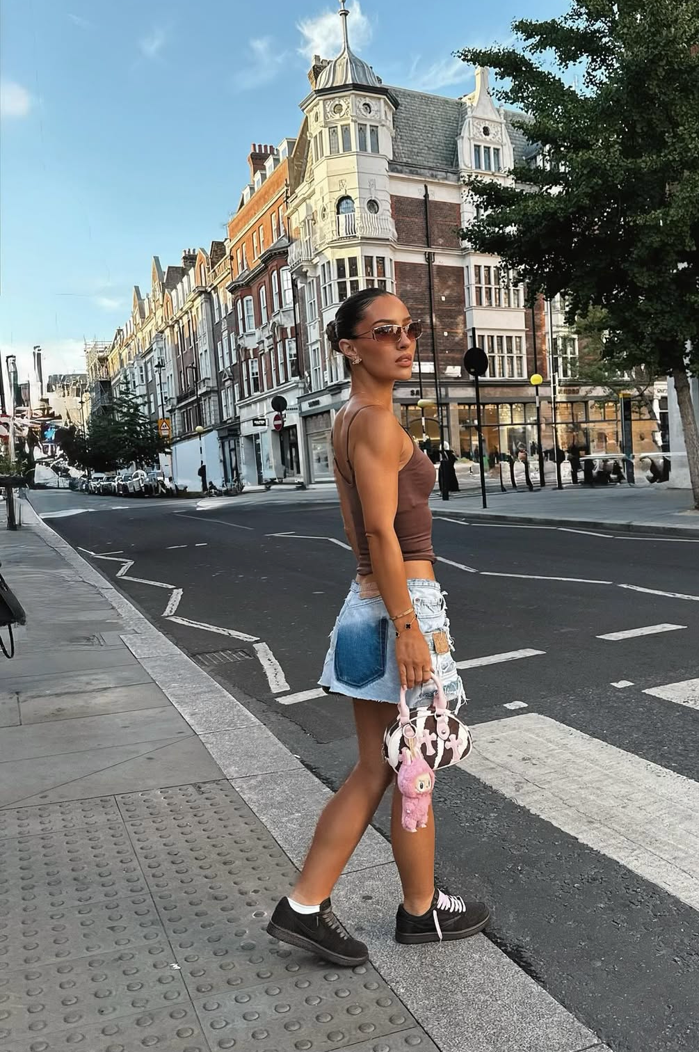 Person walking on a street with a building and trees in the background