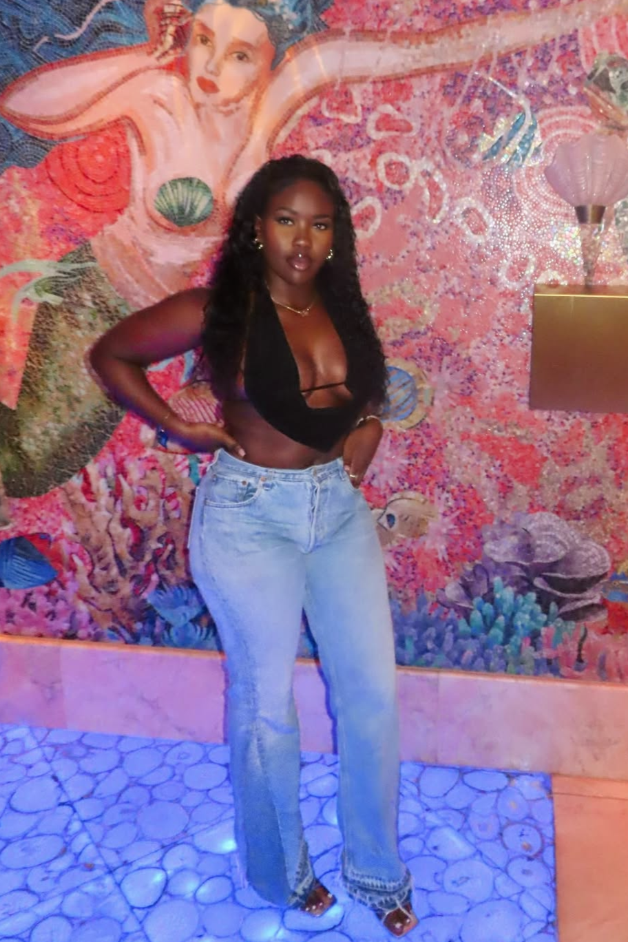 Woman posing in front of a colorful mermaid mural wearing reworked vintage levi jeans customised to her measurements