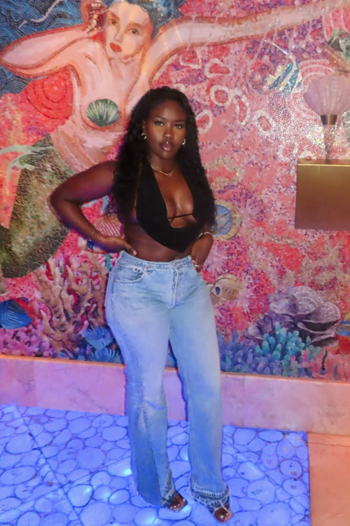 Woman posing in front of a colorful mermaid mural wearing reworked vintage levi jeans customised to her measurements