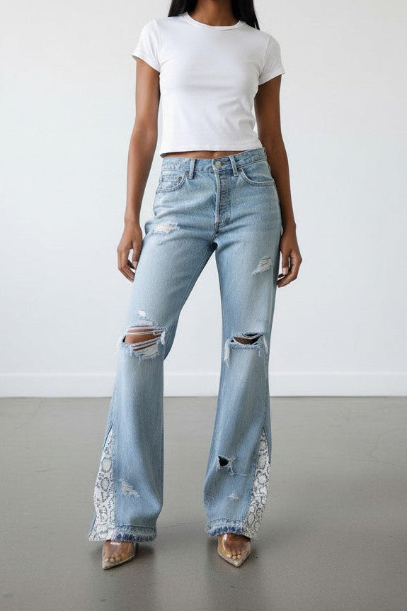 Woman wearing a white t-shirt and light blue ripped jeans against a plain background